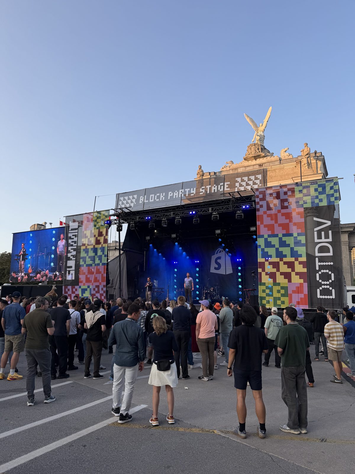 The DotDev 2026 block party stage at dusk, crowd gathered